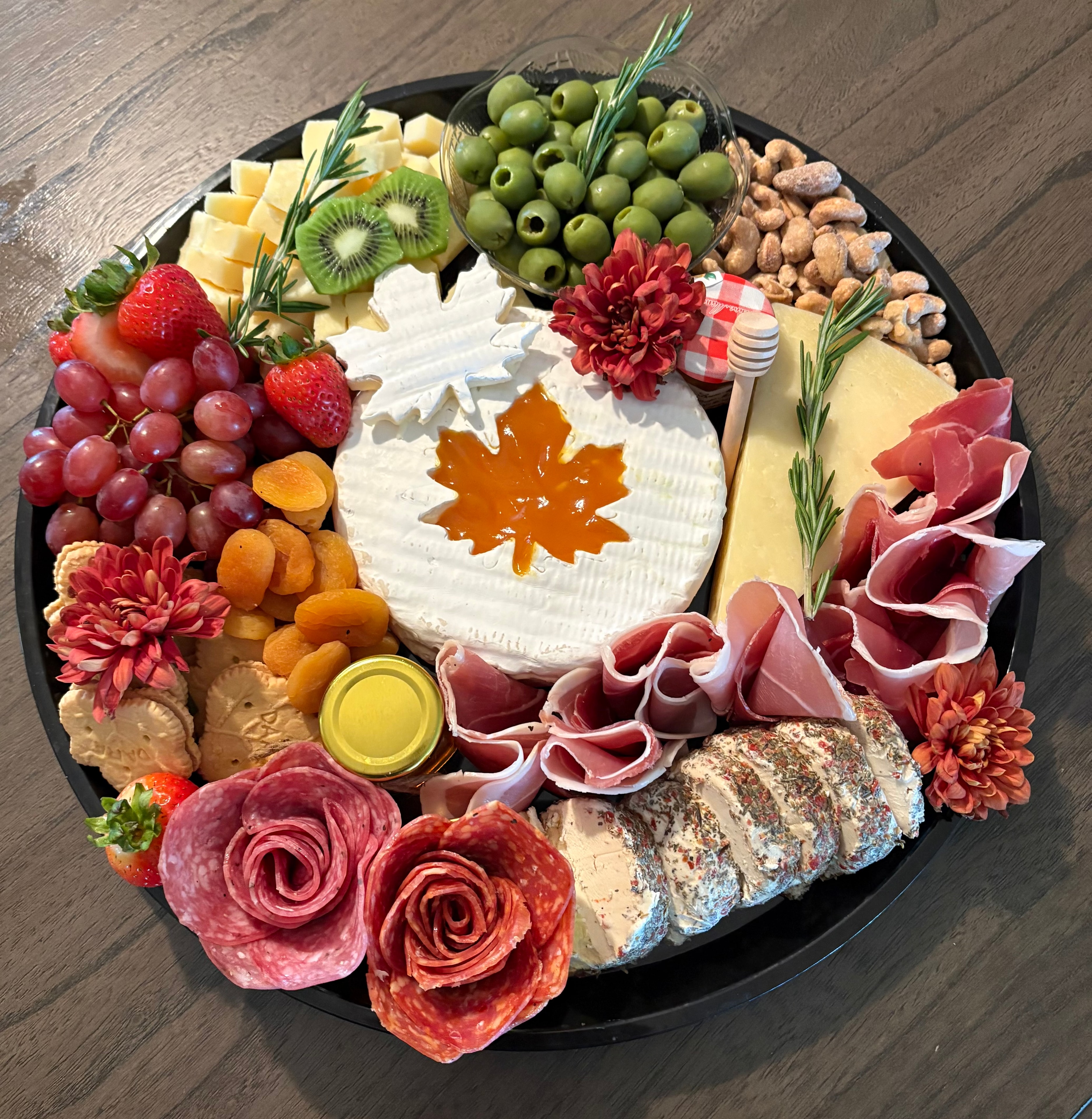 Hunt & Honey Honey & Harvest Platter with brie centerpiece, apricot jam, salami roses, prosciutto, fresh fruit, goat cheese, olives, apricots, nuts and seasonal flowers